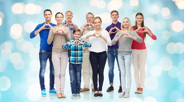 Group of smiling people showing heart hand sign — Stockfoto