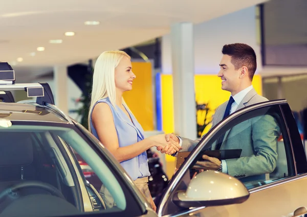 Glückliche Frau mit Autohändler in Auto-Show oder Salon — Stockfoto