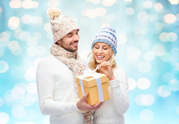 Smiling couple in winter clothes with gift box — Stock Photo, Image