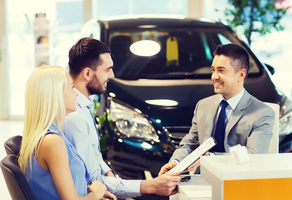 Glückliches Paar mit Autohändler in Auto-Show oder Salon — Stockfoto