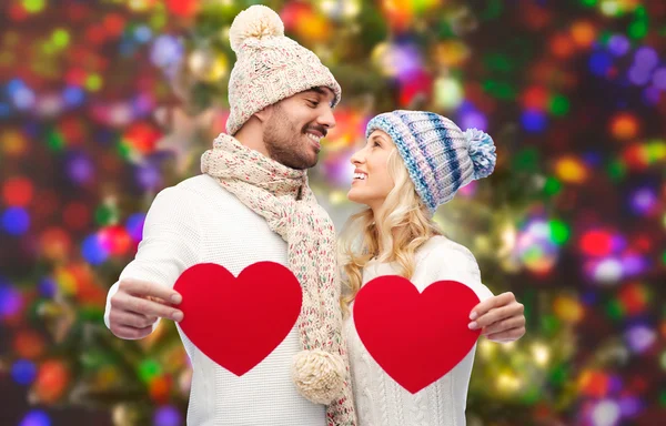 Casal sorridente em roupas de inverno com corações vermelhos — Fotografia de Stock