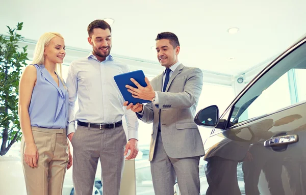 Glückliches Paar mit Autohändler in Auto-Show oder Salon — Stockfoto