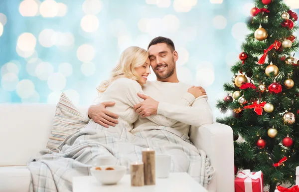 Felice coppia che abbraccia sul divano a Natale — Foto Stock