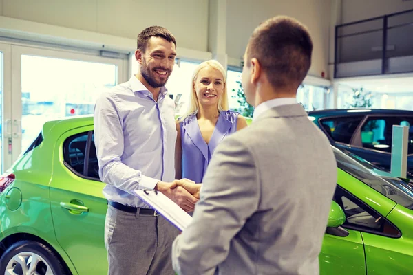 Feliz pareja con concesionario de coches en auto show o salón —  Fotos de Stock