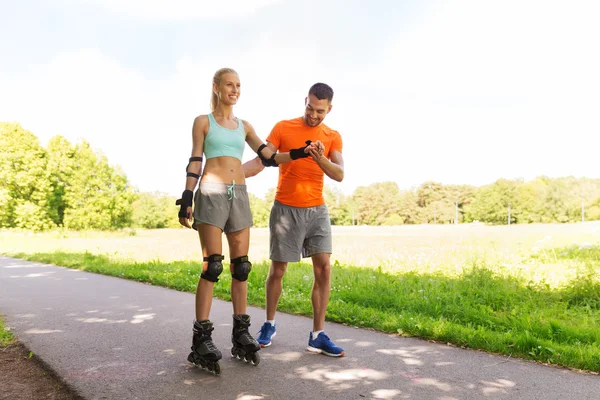 Feliz casal com patins andar ao ar livre — Fotografia de Stock