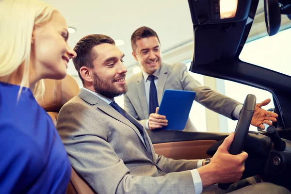 Happy couple with car dealer in auto show or salon — Stock Photo, Image