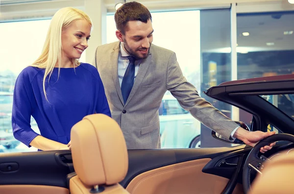 Happy couple buying car in auto show or salon — Stock Photo, Image