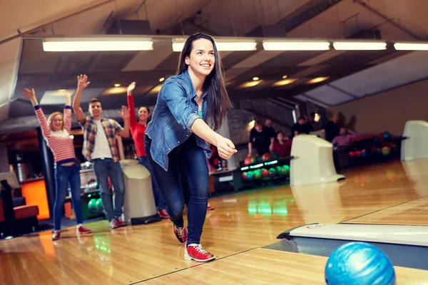 Glückliche junge Frau wirft Ball in Kegelclub — Stockfoto