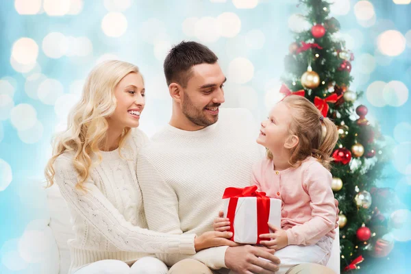 Happy family with gift box over christmas lights — Stockfoto