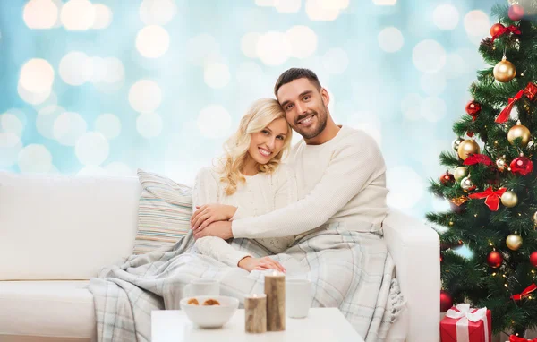 Счастливая пара обнимается на кушетке на Рождество — стоковое фото