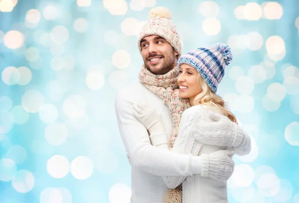 Happy couple in winter clothes hugging over lights — Stockfoto