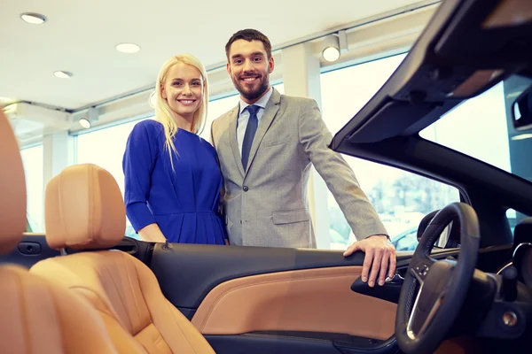 Happy couple buying car in auto show or salon — Stock Photo, Image