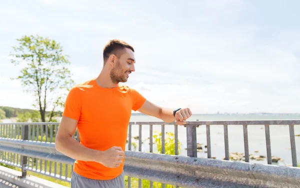 Smiling young man with smart wristwatch at seaside — Stock Photo, Image