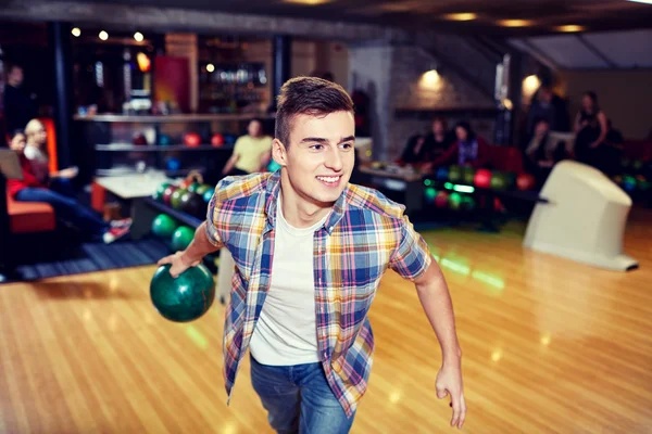 Happy young man throwing ball in bowling club — Stock Photo, Image