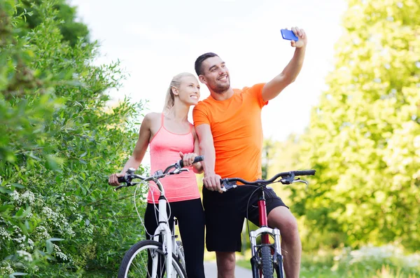 Casal com bicicleta tirando selfie por smartphone — Fotografia de Stock