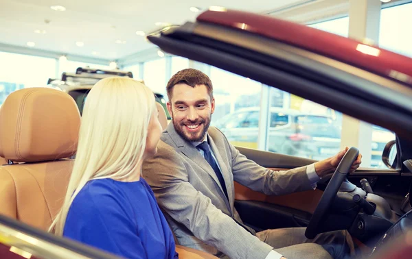 Happy couple buying car in auto show or salon — Stock Photo, Image