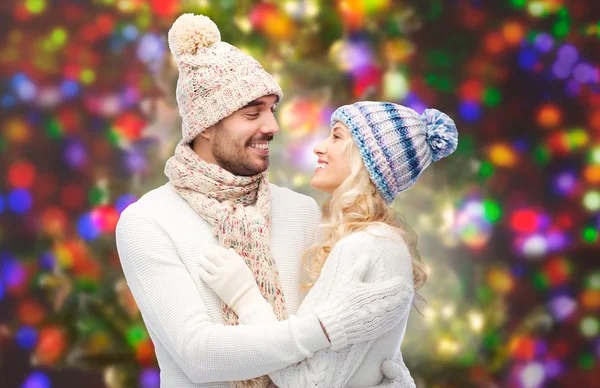 Happy couple in winter clothes hugging over lights — Stock Fotó