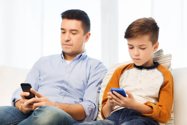 Pai e filho com smartphones em casa — Fotografia de Stock