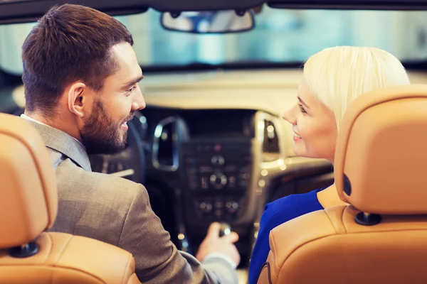 Casal feliz sentado no carro no auto show ou salão — Fotografia de Stock
