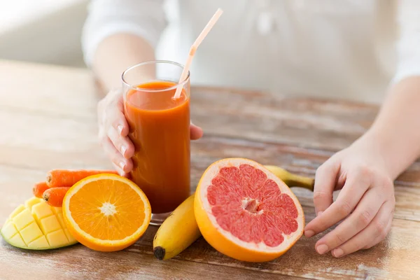 Närbild på kvinna händer med juice och frukt — Stockfoto