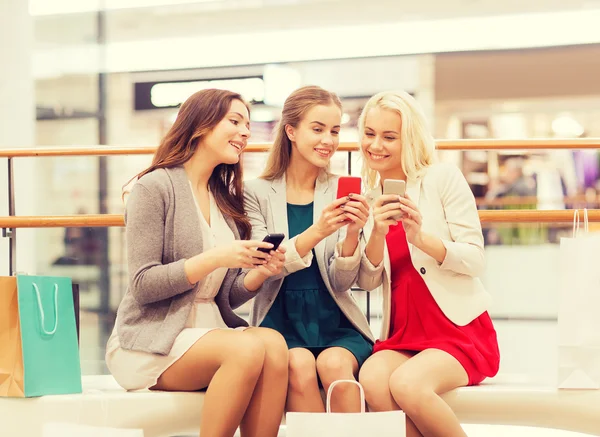 Mulheres felizes com smartphones e sacos de compras — Fotografia de Stock