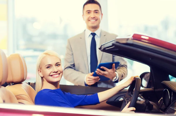 Mulher feliz com negociante de carro em auto show ou salão de beleza — Fotografia de Stock