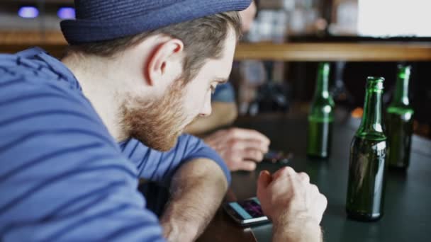 Amigos varones con smartphones bebiendo cerveza en el bar — Vídeo de stock