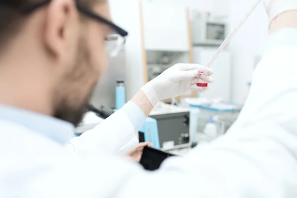 Close up de cientista com tubo e pipeta em laboratório — Fotografia de Stock