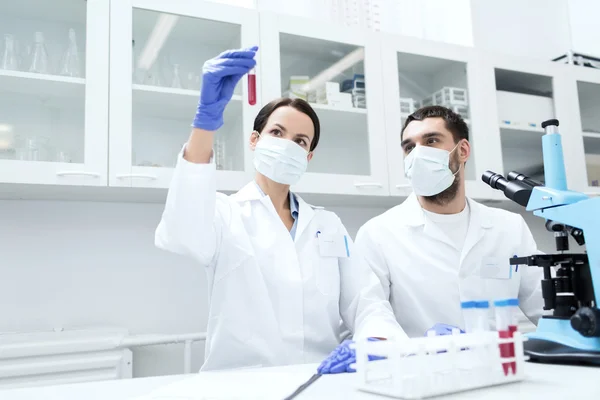 Jóvenes científicos haciendo pruebas o investigaciones en laboratorio — Foto de Stock