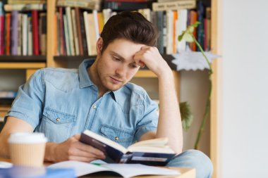 male student reading book in library clipart