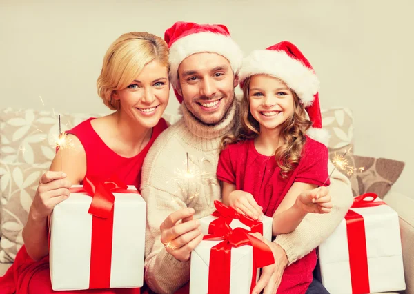 Familia sonriente sosteniendo cajas de regalo y destellos — Foto de Stock