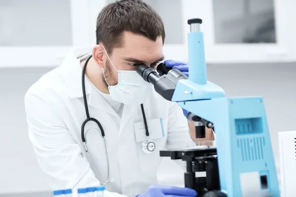 Jovem cientista olhando para microscópio em laboratório — Fotografia de Stock