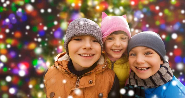 Happy children over snow and christmas lights — Stockfoto