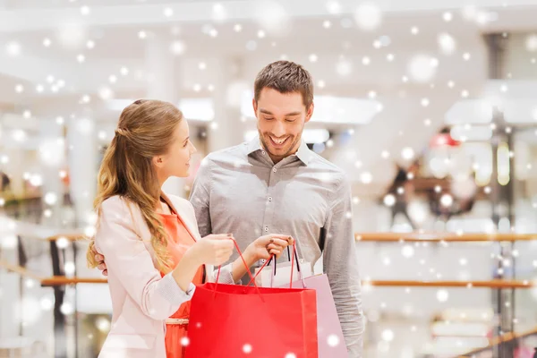 Lyckligt ungt par med shoppingväskor i köpcentret — Stockfoto