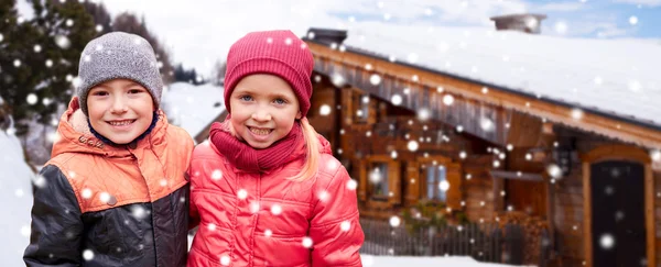 Happy girl hugging boy over country house and snow — Stock fotografie