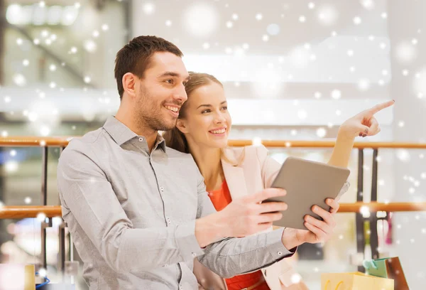 Pareja con tablet pc y bolsas de compras en el centro comercial —  Fotos de Stock