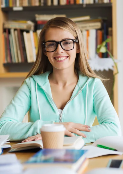 Felice studentessa con libro e caffè in biblioteca — Foto Stock