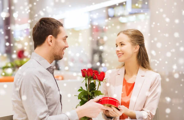 Gelukkige paar met heden en bloemen in winkelcentrum — Stockfoto