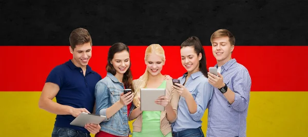Estudiantes sonrientes usando teléfonos inteligentes y tableta PC — Foto de Stock