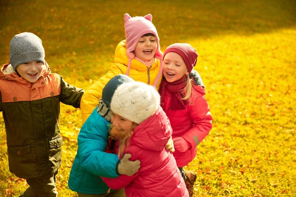 Group of happy children hugging in autumn park — Stock Photo, Image