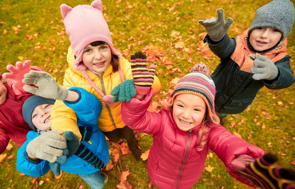 Niños felices saludando las manos en el parque de otoño —  Fotos de Stock