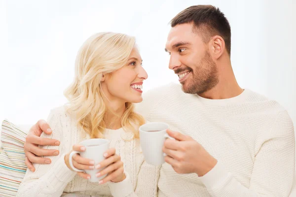 Happy couple with cups drinking tea at home — Stock Photo, Image