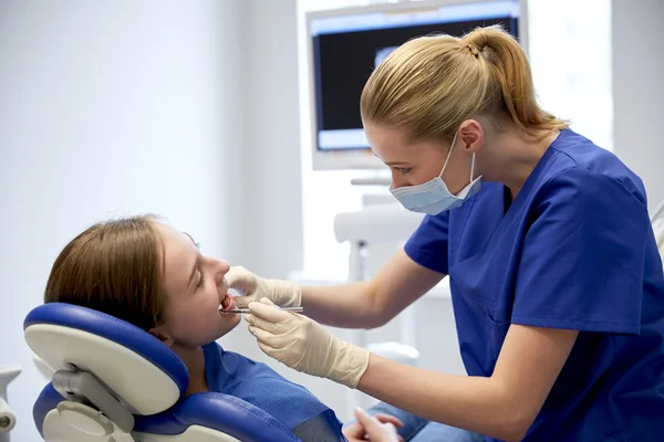 Dentista femenino chequeando dientes de niña paciente — Foto de Stock