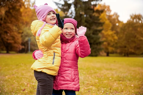 Joyeuses petites filles agitant les mains dans le parc d'automne — Photo