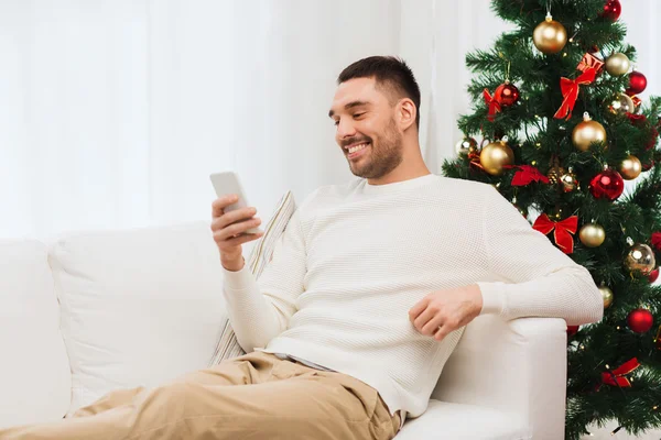 スマート フォンで自宅のクリスマスの笑みを浮かべて男 — ストック写真