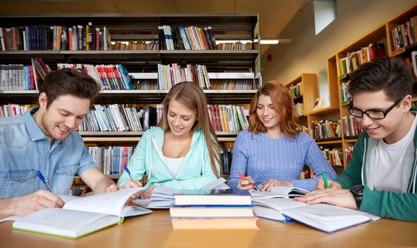 Gelukkig studenten schrijven naar laptops in bibliotheek — Stockfoto