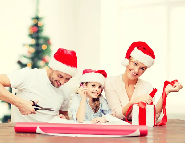 Familia sonriente en sombreros de Santa Helper con caja de regalo —  Fotos de Stock