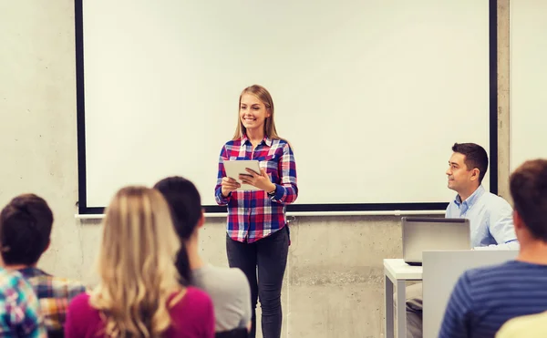 Group of smiling students and teacher in classroom — Stock Photo, Image