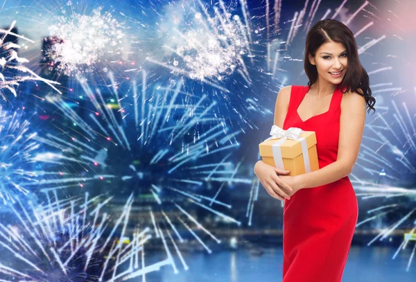 Happy woman in red dress with gift over firework — Stok fotoğraf