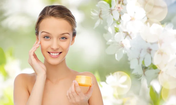 Felice giovane donna applicando crema al suo viso — Foto Stock